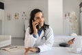 Positive young Latin cardiologist doctor woman talking on mobile phone Royalty Free Stock Photo