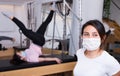 Young Latina in protective mask practicing pilates on reformer Royalty Free Stock Photo