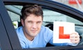 Positive young male driver holding a L sign