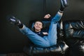 Positive young man in casual clothes lying on a black leather sofa with his legs up, looking into the camera and smiling. Cheerful Royalty Free Stock Photo