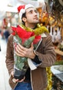 Young man in Christmas hat buying flowers and decoration at Christmas fair Royalty Free Stock Photo