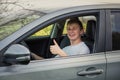 Positive young man driver showing thumb up gesture sitting in front of the steering wheel of his new car, looking excited to Royalty Free Stock Photo