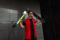 Positive young man model in a red denim vest in a T-shirt in sunglasses holding a scooter over his head. Funny cool guy hipster Royalty Free Stock Photo