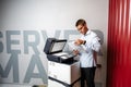 Positive young man using printer in the modern office Royalty Free Stock Photo