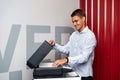 Positive young man using printer in the modern office Royalty Free Stock Photo