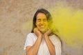 Positive young model having fun in a cloud of yellow dry powder, celebrating Holi colors festival at the desert Royalty Free Stock Photo