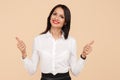 Positive young modern business woman showing thums up over beige background. Success and winner concept.