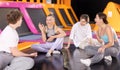 Young people sitting on platform and talking merrily in trampoline arena