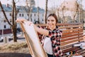 Positive young woman artist draws a picture while sitting on a bench. Smiling artist holds a wooden tablet for painting and a brus