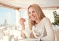 Positive young woman eating ice cream in light summer cafe Royalty Free Stock Photo