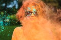 Positive young model having fun in a cloud of orange dry powder, celebrating Holi colors festival Royalty Free Stock Photo