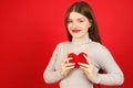 Positive young woman with a heart in her hands on a red background, a blood donor volunteer