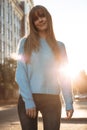 Positive young woman in oversized blue sweater standing outdoor