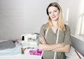 Positive young woman sewing with professional machine at workshop