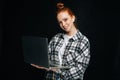 Positive young woman wearing wireless earphones holding laptop computer and looking at camera Royalty Free Stock Photo