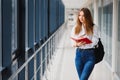 Positivity beautiful girl smiling at camera, standing on corridor with notes as backpack, going to lesson. Happy brunette female Royalty Free Stock Photo