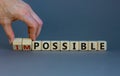 Possible or impossible. Male hand flips wooden cubes and changes the word `impossible` to `possible`. Beautiful grey backgroun Royalty Free Stock Photo