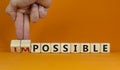 Possible or impossible. Male hand flips wooden cubes and changes the word `impossible` to `possible`. Beautiful orange backgro Royalty Free Stock Photo