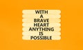 Possible symbol. Concept words With a brave heart anything is possible on wooden stick on beautiful orange table orange background Royalty Free Stock Photo