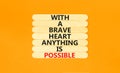 Possible symbol. Concept words With a brave heart anything is possible on wooden stick on beautiful orange table orange background Royalty Free Stock Photo