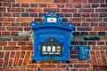 Post box of blue painted metal on red brick wall