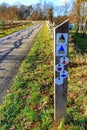 Post with hiking and cycling trail signs on side of a path between wooden fences Royalty Free Stock Photo