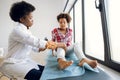 Post traumatic rehabilitation, sport physical therapy, osteopathy. Afro kid girl with a sore knee at the doctor& x27;s office Royalty Free Stock Photo