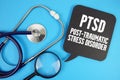 Post-Traumatic Stress Disorder (PTSD)text with Stethoscope and magnifying glass on blue background Royalty Free Stock Photo