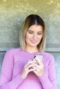Post-Workout Bliss: Blonde Millennial Woman in Pink Sports Outfit Enjoying Her Smartphone