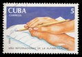 Postage stamp printed in Cuba shows a hand helping someone else to write, International Literacy year