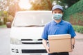 Postal delivery courier man wearing protective face mask in front of cargo van delivering package holding box due to Coronavirus Royalty Free Stock Photo