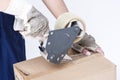 Postal and Moving. Closeup of Female Hands Packing Cardboard Box Indoors Unsing A Tape-Machine Royalty Free Stock Photo