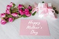 Postcard with bouquet of pink roses, gift box, on rustic wooden background. Happy mothers day text sign. Royalty Free Stock Photo