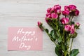 Postcard with bouquet of small pink roses on white rustic wooden background. Happy mothers day text sign. Greeting card Royalty Free Stock Photo