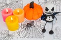 Postcard for Halloween, candles with pumpkin, spider and ghost doll. On a red background with a cobweb.