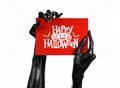 Postcard and Happy Halloween theme: black hand of death holding a paper card with the words Happy Halloween on a white isolated ba