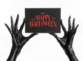 Postcard and Happy Halloween theme: black hand of death holding a paper card with the words Happy Halloween on a white isolated ba