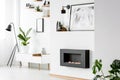 Poster above black fireplace in white apartment interior with pl