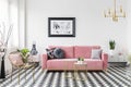 Poster above pink sofa in living room interior with gold armchair on checkered floor. Real photo Royalty Free Stock Photo