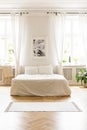 Poster above white bed in minimal bedroom interior with drapes a