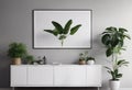 Poster above white cabinet with plant next to grey sofa in simple living room interior. Royalty Free Stock Photo