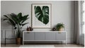 Poster above white cabinet with plant next to grey sofa in simple living room interior. Real photo Royalty Free Stock Photo