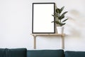 Poster in black frame in white stylish modern interior on a wall above green sofa. Design template mockup Royalty Free Stock Photo