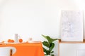 Poster on cabinet next to plant and table with orange cloth in white dining room interior Royalty Free Stock Photo