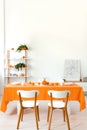 Poster on cabinet in white and orange dining room interior with wooden chairs at table Royalty Free Stock Photo