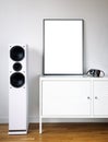 Poster Frame Mockup in white modern interior. Modern audio stereo system with white speakers on bureau in modern interior. Royalty Free Stock Photo