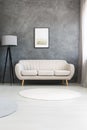 Poster on a gray wall, above a beige, leather sofa and a tripod Royalty Free Stock Photo