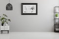 Poster on grey wall in empty living room interior with lamp above plant on cabinet. Real photo. Place for your sofa Royalty Free Stock Photo