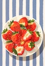 Poster with juicy strawberry on a plate and striped background