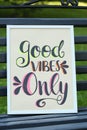 Poster with phrase Good Vibes Only on black wooden bench outdoors